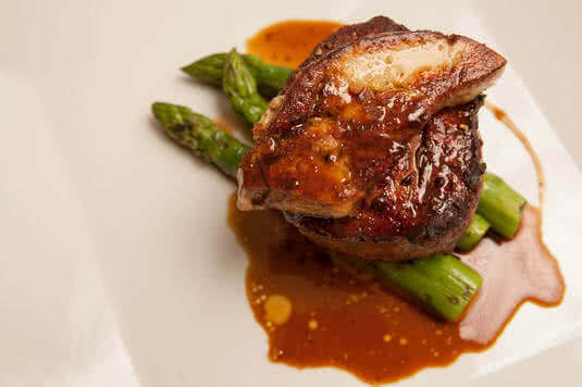 Grilled sirloin with duck paté over fresh asparagus, with our special sauce. A great taste.
